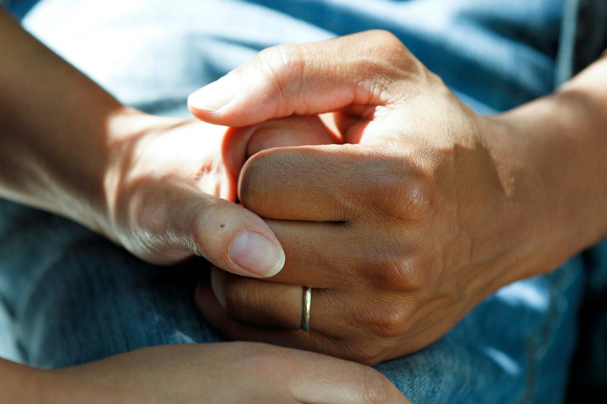 One person's hands gently holding another's.
