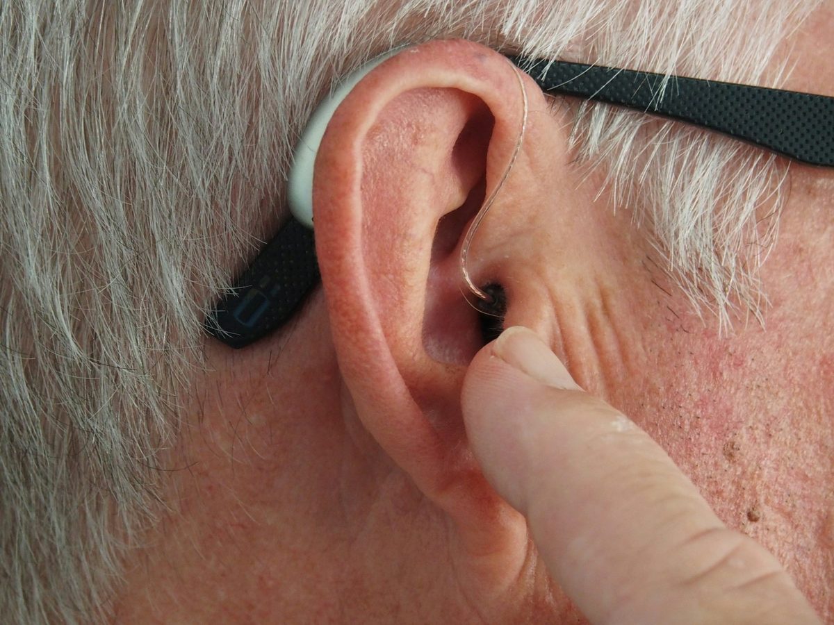 A close-up of a hearing aid being carefully fitted to an ear.
