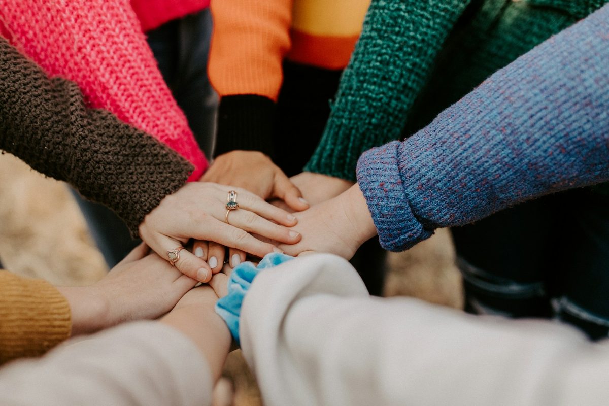 Many hands stacked together in the center of a circle.